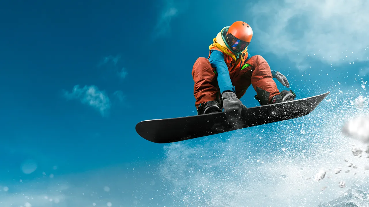 En snowboardåkare som gör ett hopp mot en blå himmel.
